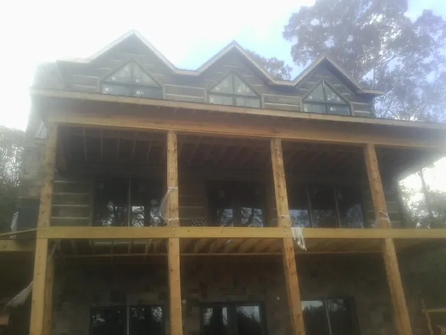 Dormers and porch framing on a large log home under construction — Roof Coating work by our crew in Felton