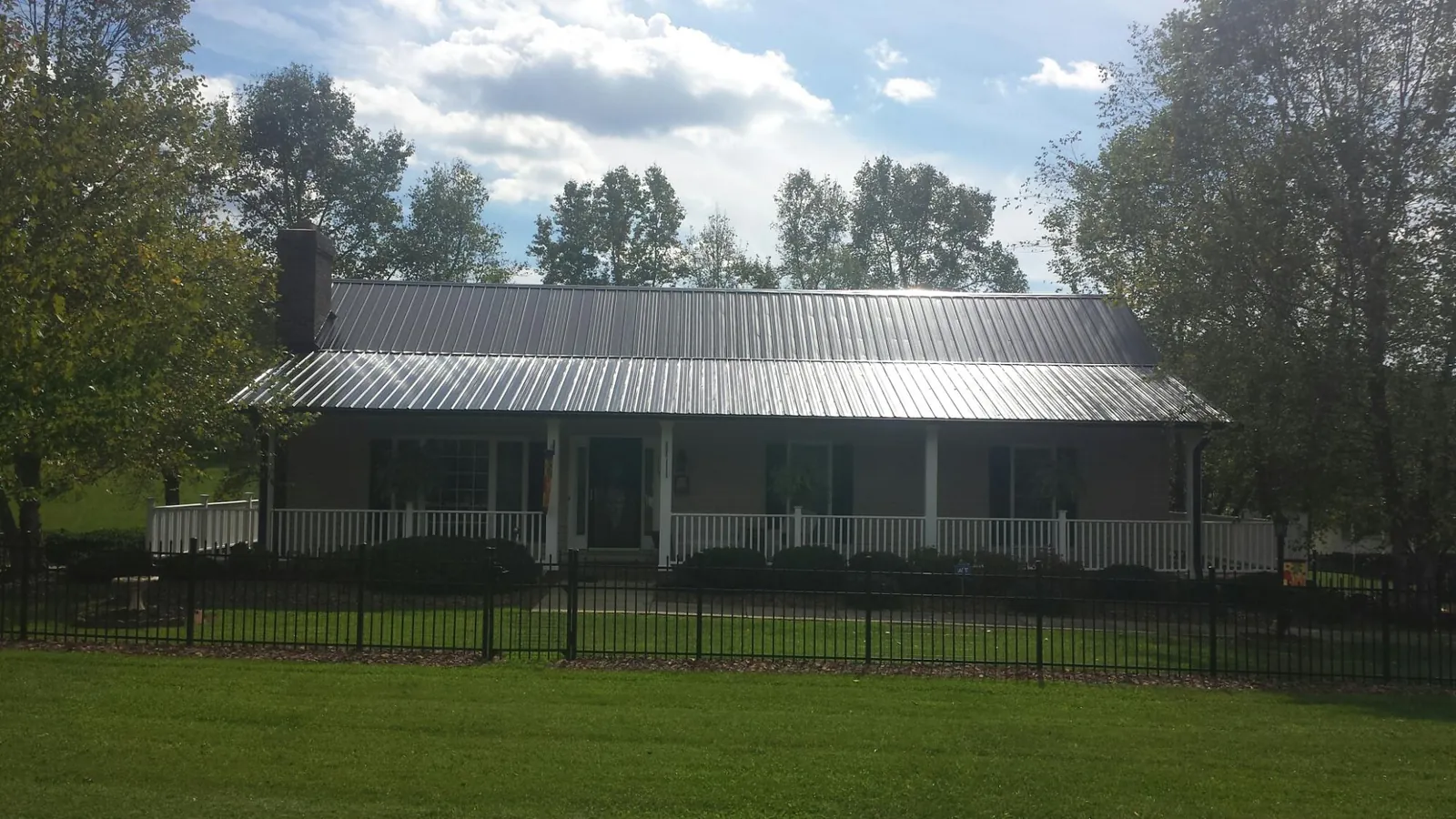 Gray metal roof on a brick ranch with a full width front porch — Gutter Guard Installation work by our crew in Felton