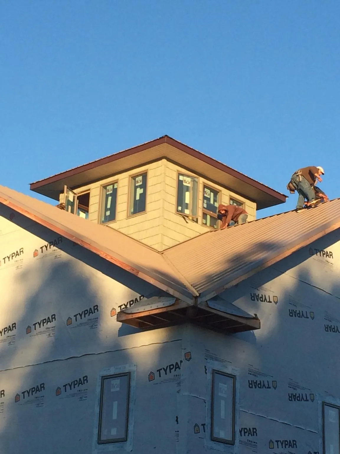 Roofers working around a rooftop cupola on a new metal roof at sunset — Roof Waterproofing in Felton by Roofing Brothers